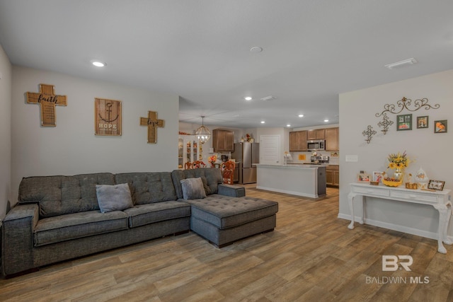 living room with light hardwood / wood-style floors and a notable chandelier