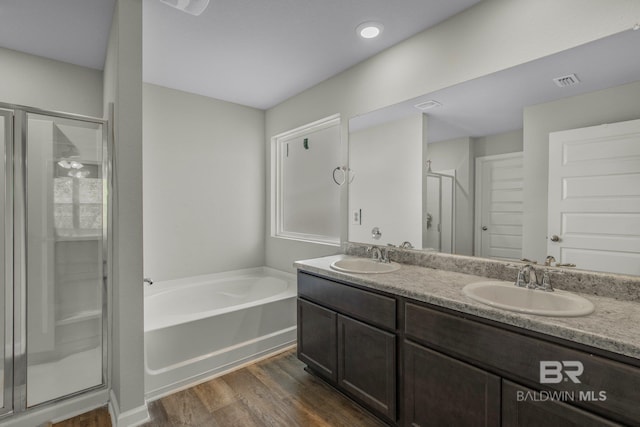 bathroom featuring wood-type flooring, plus walk in shower, and vanity