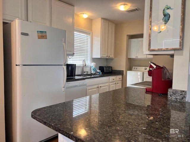 kitchen featuring white appliances, dark stone countertops, independent washer and dryer, and white cabinetry