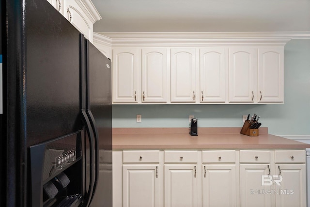 1521 E Peyton Dr, Mobile, AL 36695 - kitchen with black fridge, light countertops, and white cabinetry