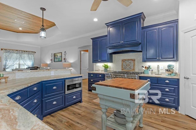 kitchen featuring stainless steel appliances, light stone countertops, hanging light fixtures, blue cabinetry, and light wood-type flooring