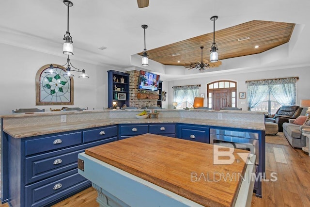 kitchen featuring a center island, a tray ceiling, light hardwood / wood-style flooring, and blue cabinets