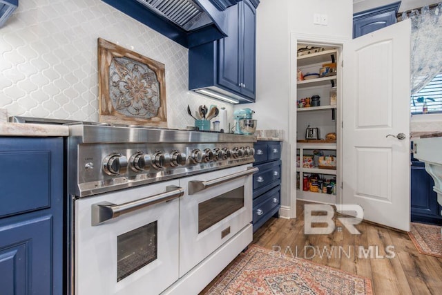 kitchen featuring dark wood-type flooring, double oven range, premium range hood, and blue cabinets