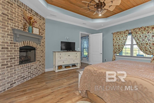 bedroom with ornamental molding, wood ceiling, a tray ceiling, ceiling fan, and light hardwood / wood-style flooring