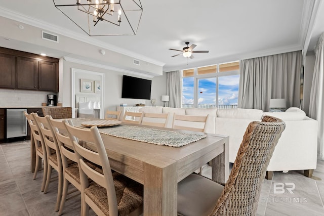 tiled dining room featuring ceiling fan with notable chandelier and ornamental molding