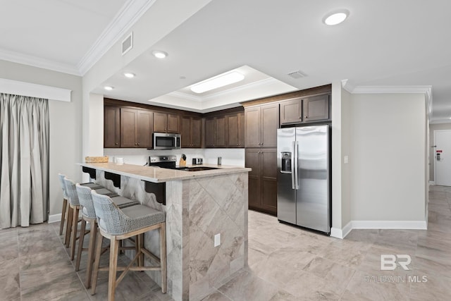 kitchen featuring kitchen peninsula, crown molding, a breakfast bar area, dark brown cabinets, and appliances with stainless steel finishes