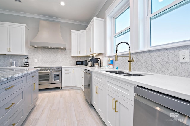 kitchen with sink, white cabinets, backsplash, custom exhaust hood, and stainless steel appliances