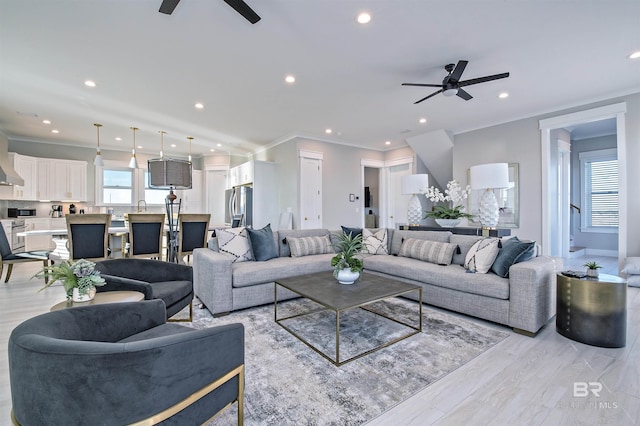 living room with ornamental molding, sink, and ceiling fan