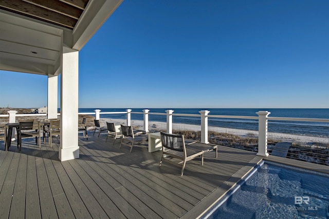 wooden terrace featuring a water view and a view of the beach