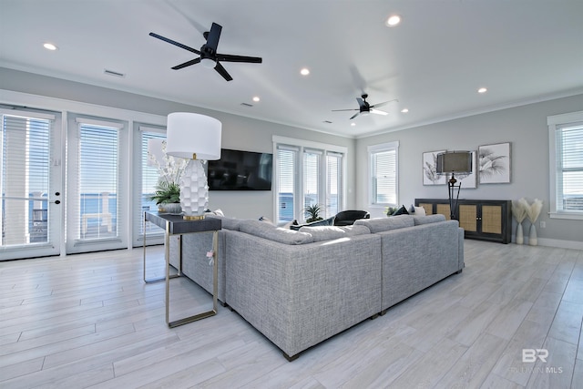 living room featuring crown molding, a healthy amount of sunlight, and light wood-type flooring