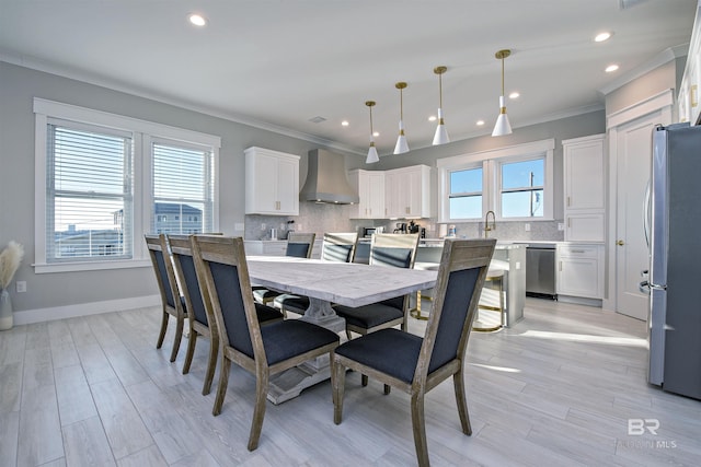 dining space featuring ornamental molding, plenty of natural light, sink, and light hardwood / wood-style flooring