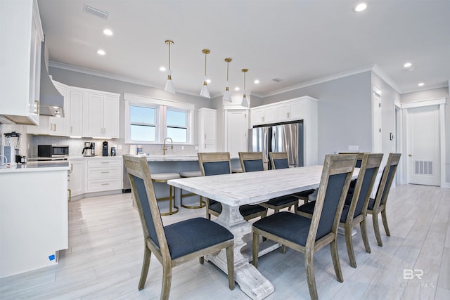 dining area with ornamental molding, sink, and light hardwood / wood-style floors