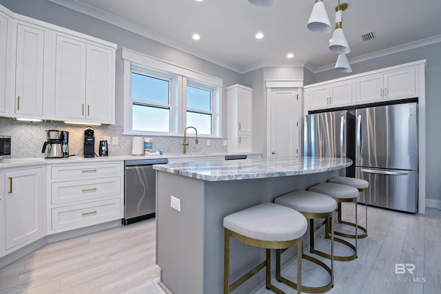 kitchen with white cabinetry, light stone counters, a center island, hanging light fixtures, and appliances with stainless steel finishes