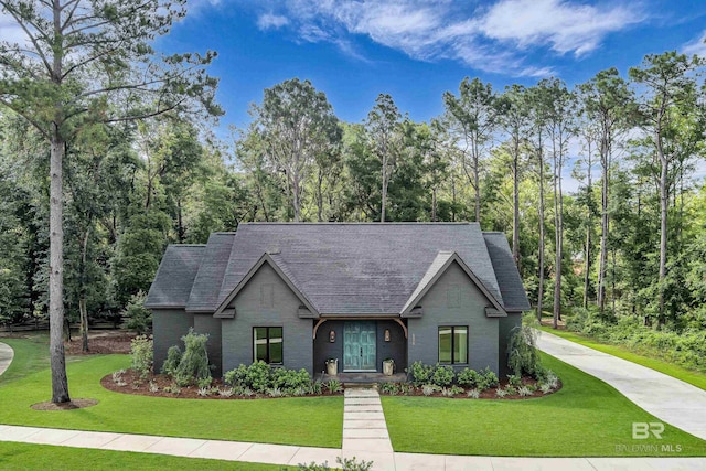 view of front facade featuring a shingled roof, a front lawn, and brick siding