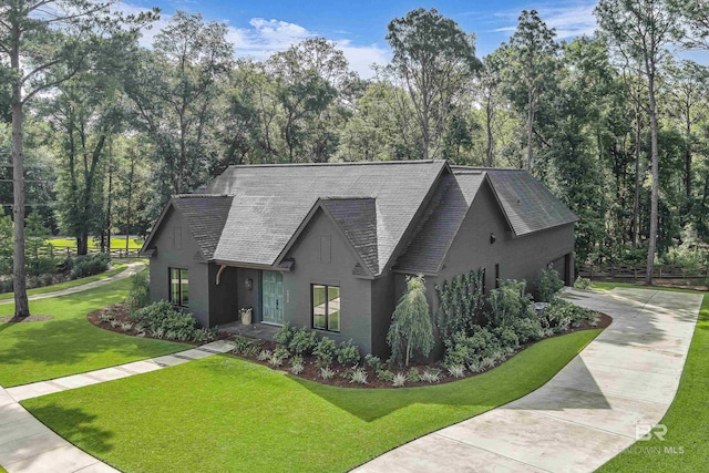 view of front of house featuring driveway, stucco siding, a shingled roof, and a front yard