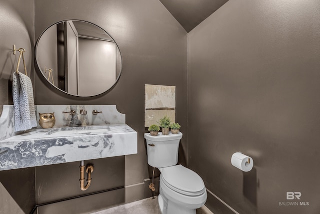 bathroom with toilet, a sink, lofted ceiling, and baseboards