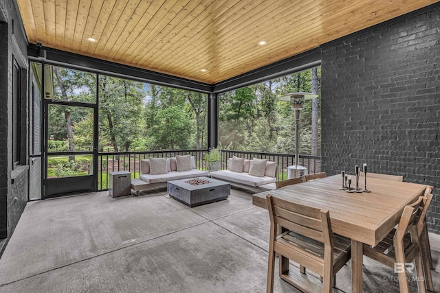 sunroom with an outdoor living space with a fire pit and view of scattered trees