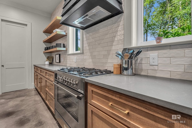 kitchen with high end stainless steel range, wall chimney exhaust hood, open shelves, backsplash, and finished concrete flooring