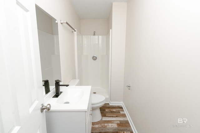 bathroom with hardwood / wood-style floors, vanity, toilet, and walk in shower