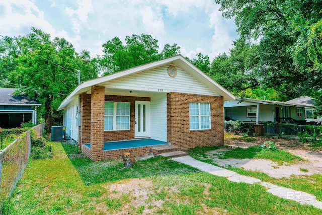 bungalow with covered porch, a front lawn, and central AC unit