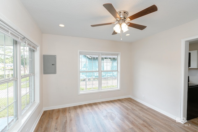 unfurnished room featuring ceiling fan, a textured ceiling, electric panel, and light hardwood / wood-style flooring