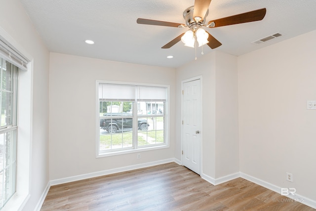 unfurnished room with ceiling fan, light wood-type flooring, and a textured ceiling