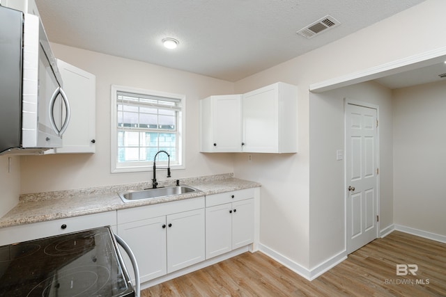 kitchen featuring white cabinets, range, and sink