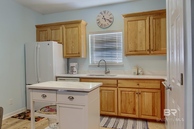 kitchen featuring light wood-type flooring, light countertops, a sink, and baseboards