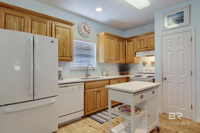 kitchen featuring light countertops, a sink, light wood-type flooring, white appliances, and under cabinet range hood