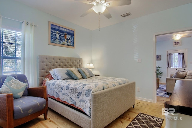 bedroom featuring light wood-type flooring, baseboards, visible vents, and a ceiling fan