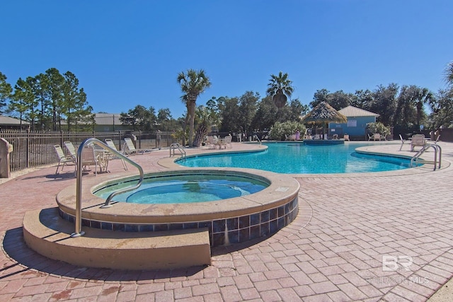 pool featuring fence, a hot tub, and a patio