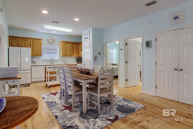 kitchen with light countertops, white appliances, visible vents, and light wood-style flooring