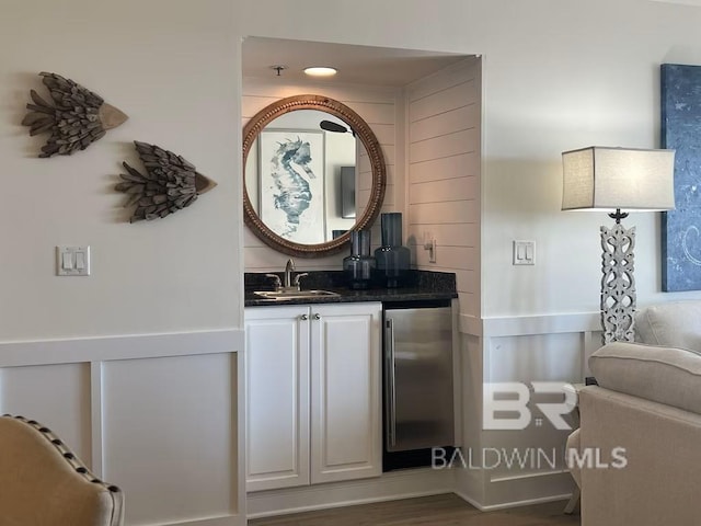 bar with stainless steel refrigerator, white cabinetry, dark hardwood / wood-style floors, and sink