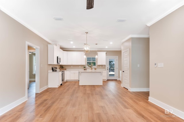 kitchen featuring crown molding, a kitchen island, light countertops, light wood-style flooring, and stainless steel appliances