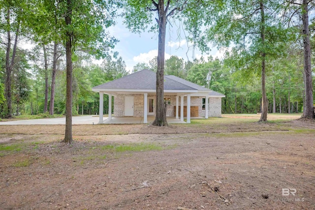view of front facade with roof with shingles, concrete driveway, and brick siding
