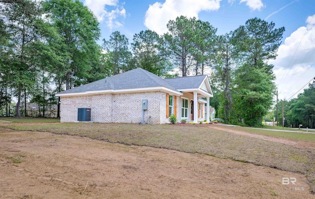view of side of home with brick siding and a shingled roof