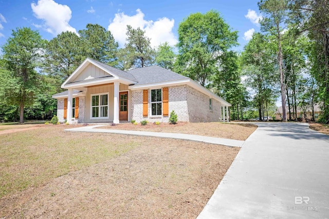 view of front of home with board and batten siding, a front yard, driveway, and brick siding