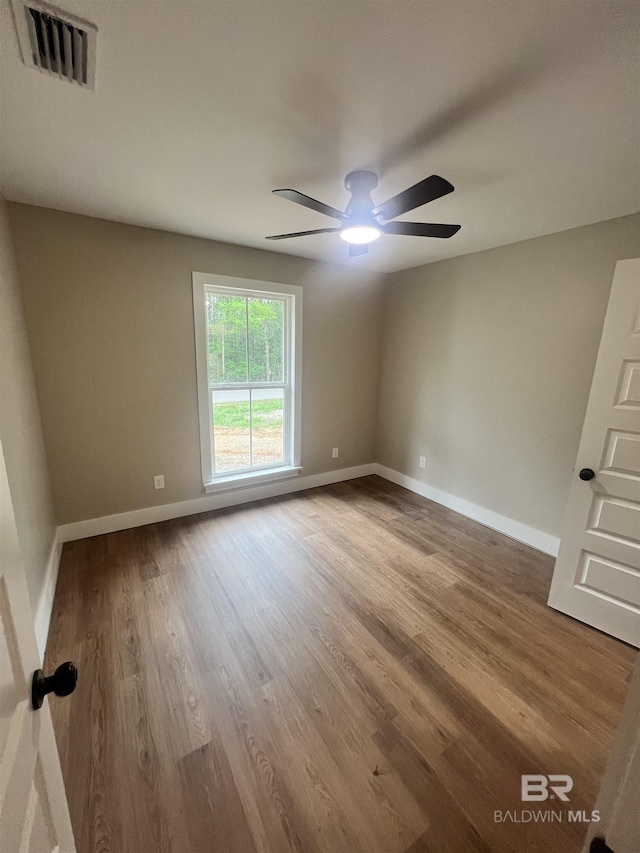 empty room featuring visible vents, baseboards, ceiling fan, and wood finished floors
