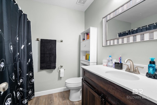 bathroom with toilet, vanity, and hardwood / wood-style floors