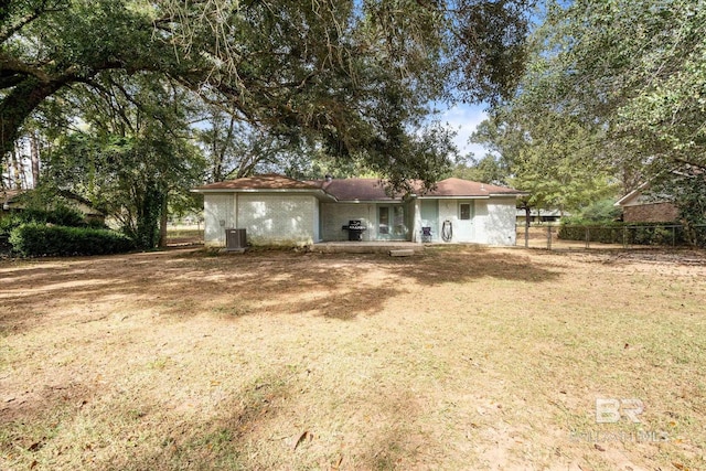 rear view of property featuring a yard and cooling unit