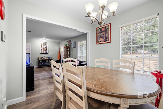 dining room with dark wood-type flooring and an inviting chandelier