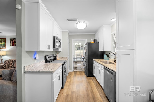 kitchen with light stone counters, white cabinetry, appliances with stainless steel finishes, sink, and light hardwood / wood-style floors