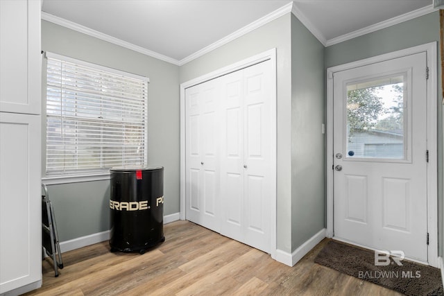 foyer with ornamental molding and light hardwood / wood-style floors