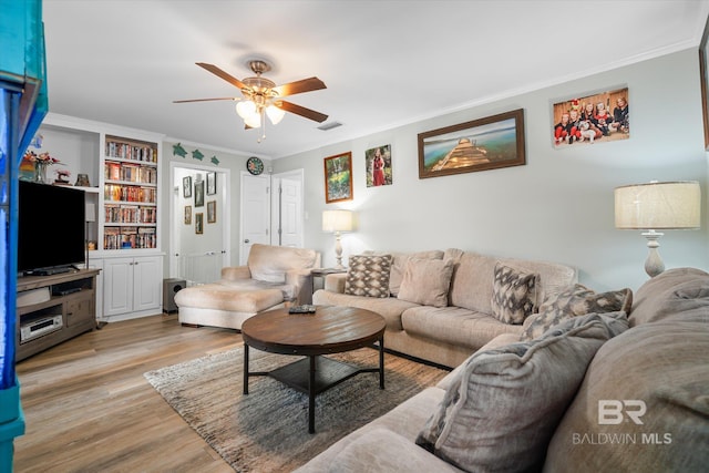 living room featuring built in features, light wood-type flooring, ceiling fan, and ornamental molding