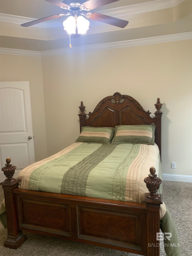 carpeted bedroom with ornamental molding, ceiling fan, and a tray ceiling