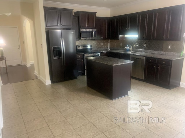 kitchen featuring tasteful backsplash, stainless steel appliances, dark brown cabinets, a center island, and ornamental molding