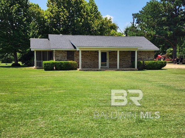 ranch-style house with a front lawn, roof with shingles, and brick siding