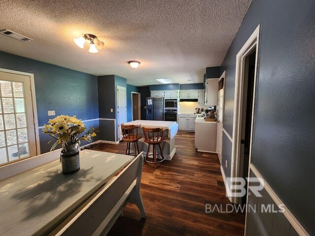 dining room with a textured ceiling and dark wood-type flooring