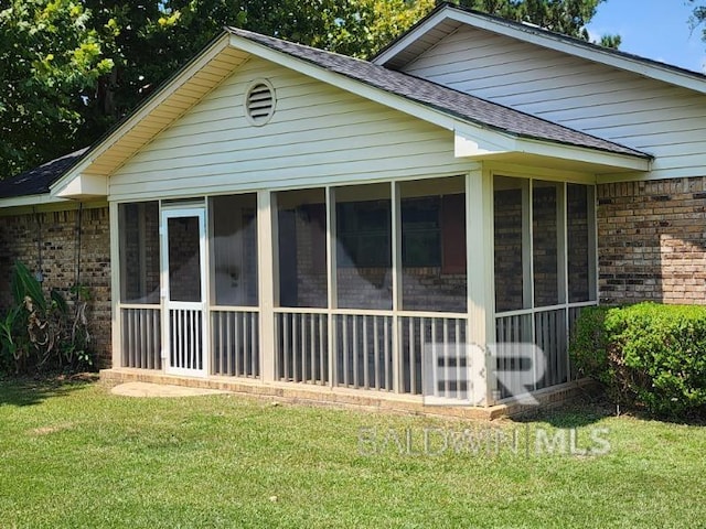 view of home's exterior with a sunroom and a lawn