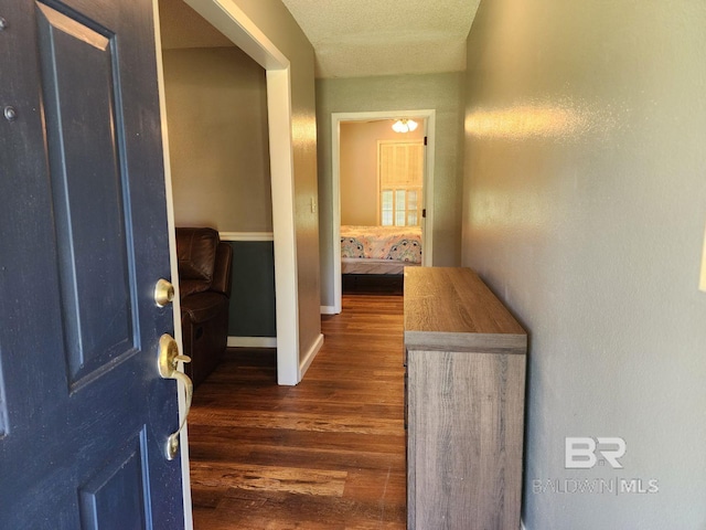 corridor with dark wood-style floors and baseboards